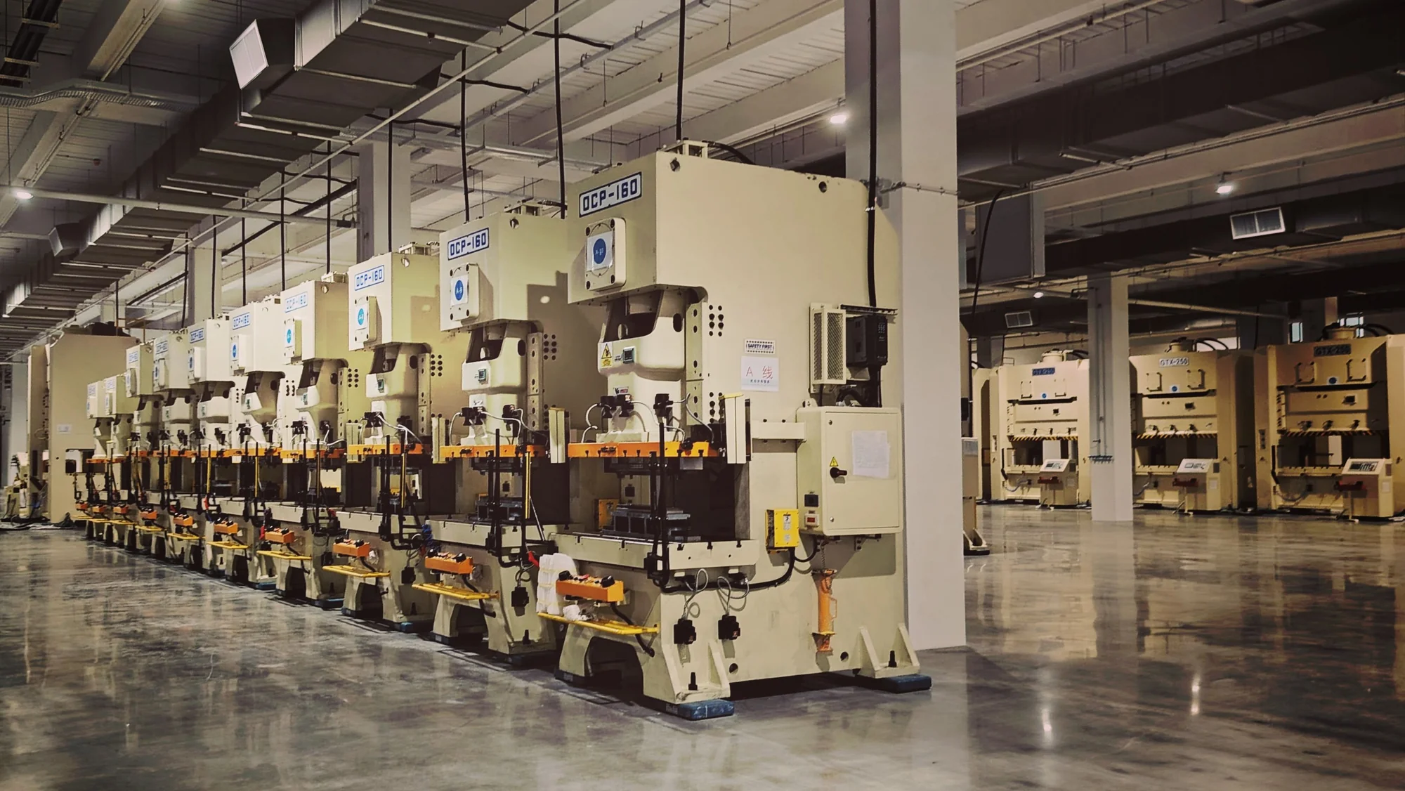 A row of industrial presses inside a spacious production hall