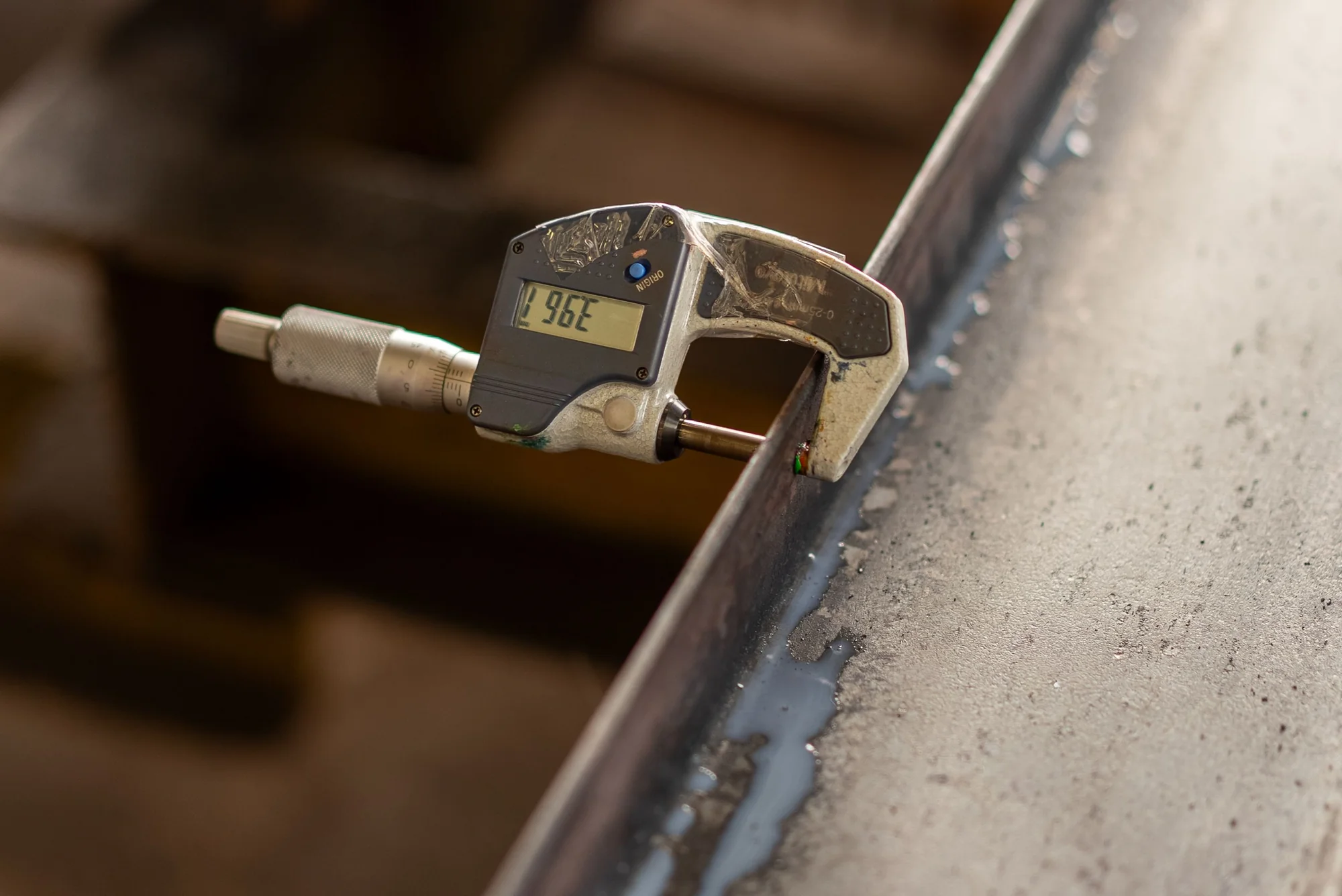 A digital micrometer measuring the thickness of a metal component