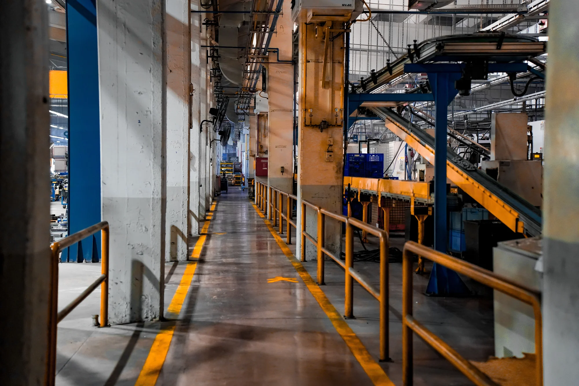 Production-floor machinery and conveyor equipment beside a marked industrial walkway
